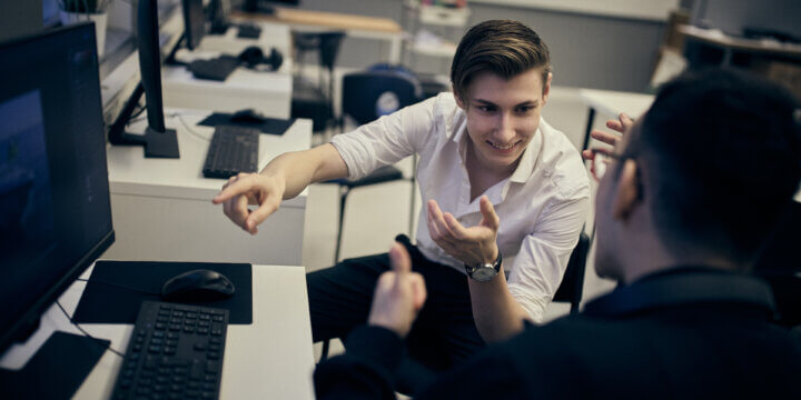 Elever diskuterar ett grupparbete på datorskärmen framför dem