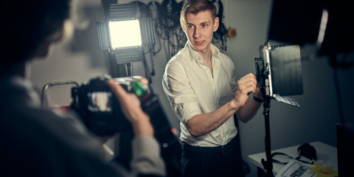 En elev ställer in en lampa och pratar med sin klasskompis som håller i en kamera