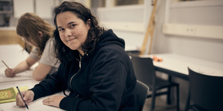 Elev sitter och skissar i ett klassrum