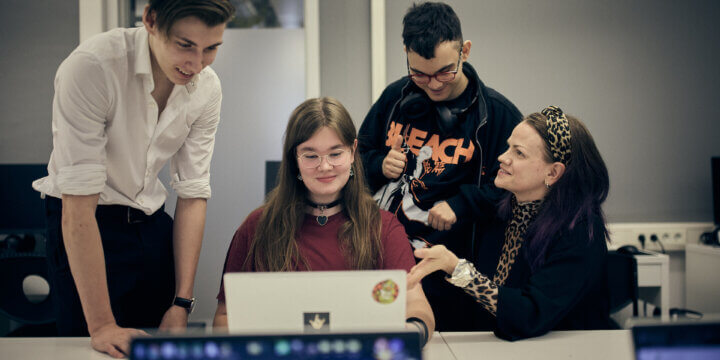 Lärare hjälper sina elever och diskuterar deras arbete på en dator